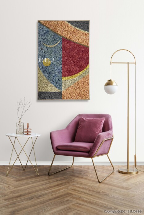 Een kamer met een modern interieur is voorzien van een roze stoel met gouden poten, een witte bijzettafel met een gouden frame en een staande lamp met een bolvormige kap. Boven de stoel hangt een abstracte, veelkleurige Abstract Machio. De kamer heeft een houten vloer en een witte muur.