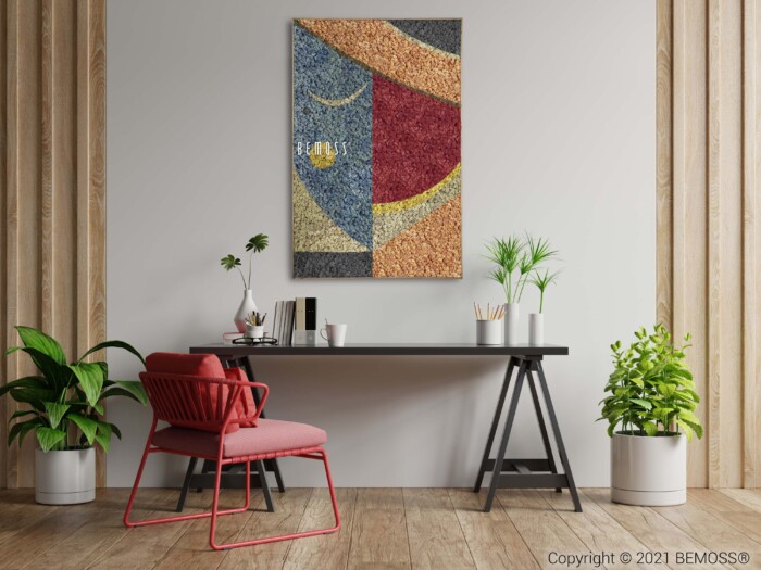 Een modern kantoor met een kleurrijk Abstract Machio kunstwerk aan de muur en een opvallende BEMOSS moswand. De werkruimte is voorzien van een zwart bureau met boeken, een plant en een laptop, aangevuld met een rode stoel met kussen. Twee groene planten flankeren de opstelling en voegen een vleugje natuur toe aan de minimalistische kamer.