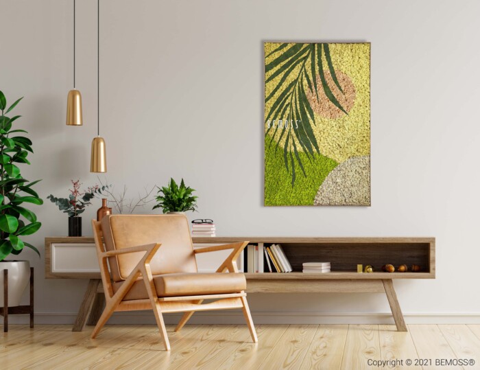 Een moderne woonkamer is voorzien van een lichtbruine fauteuil aan de linkerkant, een houten lage plank met boeken en decor in het midden, en een ingelijst abstract kunstwerk met groene en gele tinten aan de muur. Aan het plafond hangen twee hanglampen. Planten, waaronder een Abstract Miuzela, voegen een vleugje groen toe.