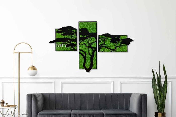 Moderne woonkamer met rechts een zwarte bank en een hoge slangenplant. Boven de bank hangt een Mosschilderij Acacia (114x188cm) met boomsilhouetten. Links staat een gouden vloerlamp met een witte bolvormige kap. Minimalistisch design met een witte muur.