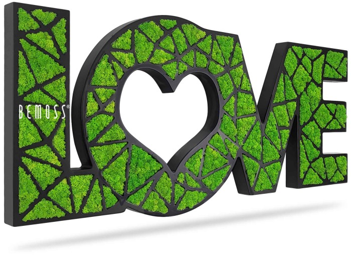 Een decoratief bord met de tekst 'LOVE', met de 'O' in de vorm van een hart. De letters zijn ontworpen met een weelderige groene mosachtige textuur tegen een zwarte achtergrond, wat een natuurlijke, levendige uitstraling geeft. Het woord 