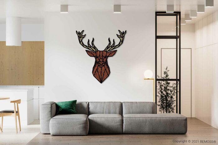 Een moderne woonkamer met een grijze hoekbank en een groen kussen, tegenover een muur met een geometrisch kunstwerk van een hertenkop. De kamer heeft een minimalistisch ontwerp met een houten schuifdeur, een BEMOSS moschilderij, een kleine potplant en een ronde lamp op een bijzettafel.