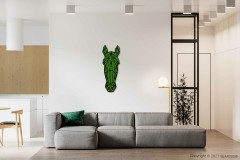 Een moderne woonkamer is voorzien van een grijze sectionele bank versierd met een enkel groen kussen. Boven de bank, aan een witte muur, hangt een opvallende BEMOSS moschilderij in de vorm van een geometrisch paardenhoofd. De kamer is minimalistisch ingericht met potplanten en biedt gedeeltelijk zicht op de keuken.