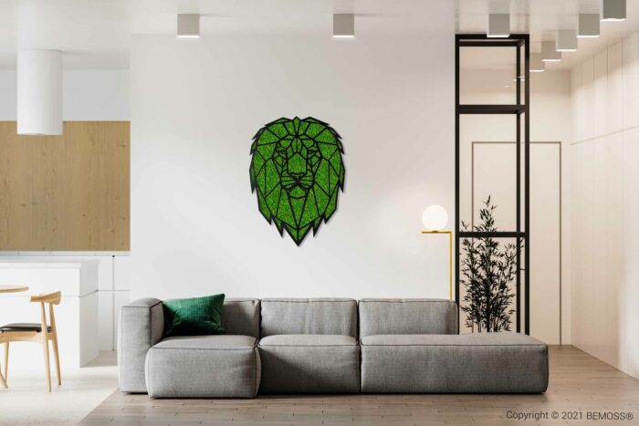 Moderne woonkamer met een grote grijze sofa, een groen sierkussen en een geometrisch kunstwerk met een groene leeuwenkop aan de muur. De ruimte is minimalistisch ingericht met een lichte houten vloer, een elegante BEMOSS-mosschilderij aan de muur, gedeeltelijk zicht op de keuken en een vloerlamp naast de bank.