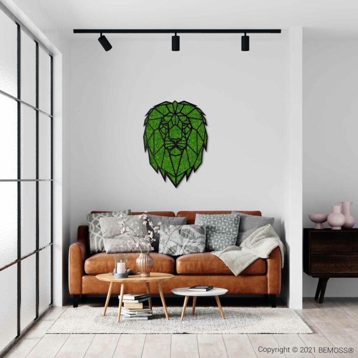 Een moderne woonkamer met een bruinleren bank versierd met kussens met verschillende patronen en een deken. Boven de bank hangt een groen mozaïekkunstwerk van een leeuwenkop, dat lijkt op een prachtige BEMOSS moswand. De kamer is voorzien van railverlichting, een houten salontafel en een dressoir met decoratieve items.