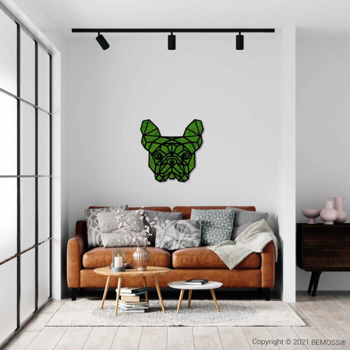 Een moderne woonkamer is voorzien van een bruinleren bank met verschillende grijze en witte kussens en een lichtgrijze plaid. Boven de bank is een geometrische groene BEMOSS-mosschilderij gemonteerd met de afbeelding van een hondengezicht. De kamer is voorzien van een ronde houten salontafel, een roze vaas en grote ramen.