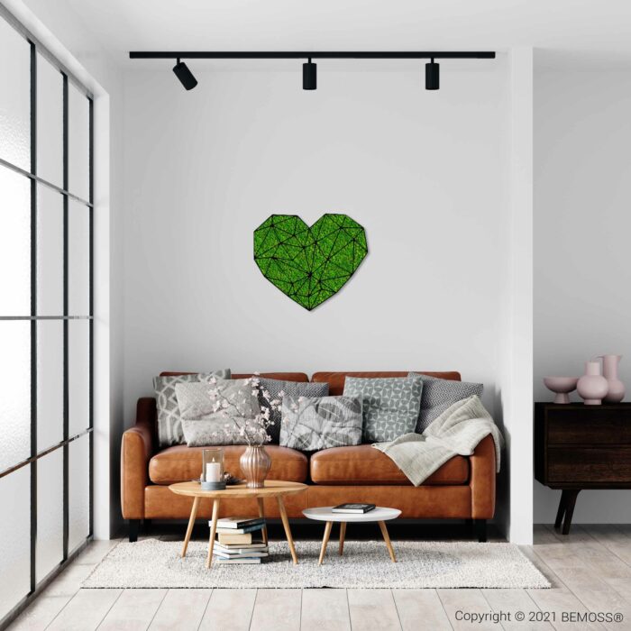 Een moderne woonkamer met een bruinleren bank, versierd met kussens met verschillende patronen en een grijze deken. Boven de bank hangt een geometrische groene moschilderij muurkunst. Er staat een ronde houten salontafel ervoor met decor en rechts een dressoir.