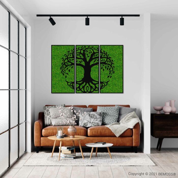 Een moderne woonkamer met een bruinleren bank versierd met grijze en witte kussens en een zachte deken. Voor de bank staat een houten salontafel met decoratieve items. Aan de muur zorgt een BEMOSS-mosschilderij met een boom op een groene achtergrond voor een milieuvriendelijke toets.