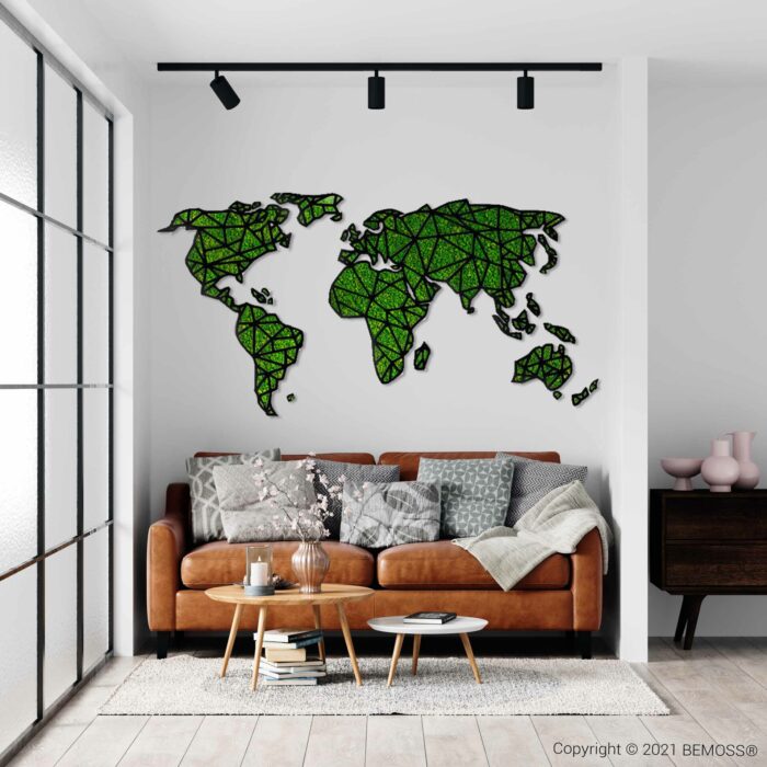Moderne woonkamer met een bruinleren bank versierd met diverse kussens en een deken. Op een glazen salontafel staat een vaas met bloemen. Boven de bank siert een artistieke groene moschilderij van de wereld de witte muur. Grote ramen laten voldoende natuurlijk licht binnen.