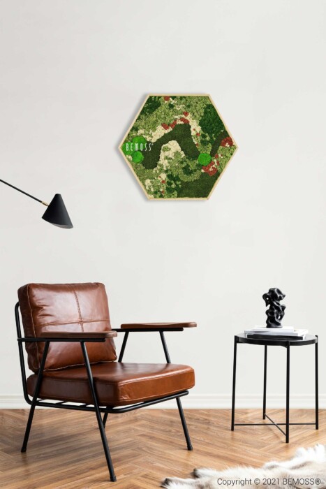Een stijlvolle kamer met een bruinleren fauteuil en een zwarte vloerlamp. Naast de stoel staat een klein zwart bijzettafeltje met een decoratief beeldhouwwerk en een boek. Aan de witte muur hangt een zeshoekige ingelijste moschilderij met de titel 