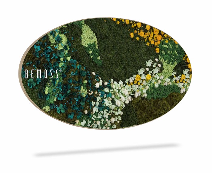 Een ovaalvormige Mosschilderij Ellips FLATMOSS van Bemoss® heeft een weelderige groene achtergrond met levendige vlekken van gele, witte en blauwgroen getextureerde elementen, die lijken op een mix van bloemen en bladeren. Het stuk is driedimensionaal met een schaduw, waardoor een zwevend effect ontstaat tegen een witte achtergrond.
