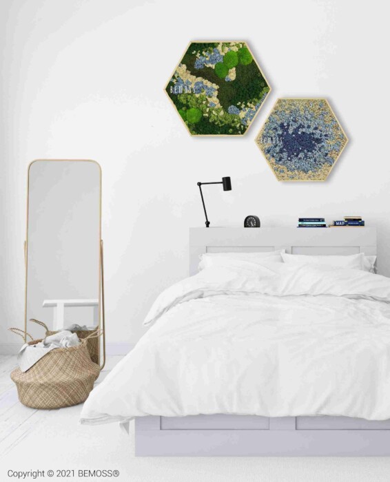 Een minimalistische slaapkamer met een wit bed, wit beddengoed, een zwarte wandlamp, een hoge spiegel, een geweven mand en twee Mosschilderij cirkel BEMOSS® ORTHO ICE kunstwerken op de witte muur boven het bed.
