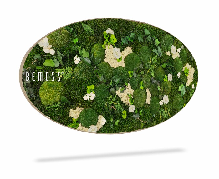 Een grote ovale Mosschilderij Ellips FLATMOSS heeft weelderig groen mos en witte bloemen, gerangschikt in ingewikkelde patronen, met de tekst 
