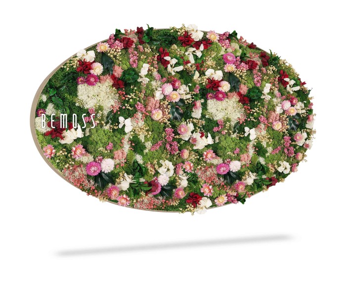 Een ovaalvormig arrangement van kleurrijke bloemen en groen, waaronder verschillende tinten roze, rood, wit en groen, met 