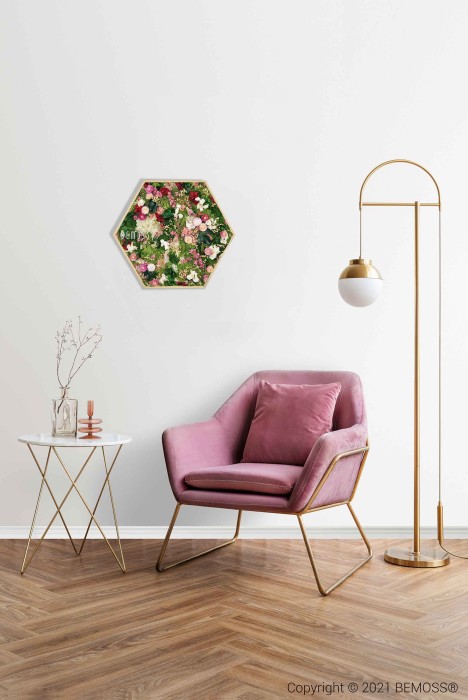 Een moderne woonkamer is voorzien van een roze fluwelen fauteuil met gouden poten, een gouden vloerlamp met een witte bolvormige kap en een witte bijzettafel met gouden poten met daarin een rieten diffuser en een kaars. Aan de witte muur boven de stoel hangt een zeshoekige Mosschilderij PLANTEN Lomo.