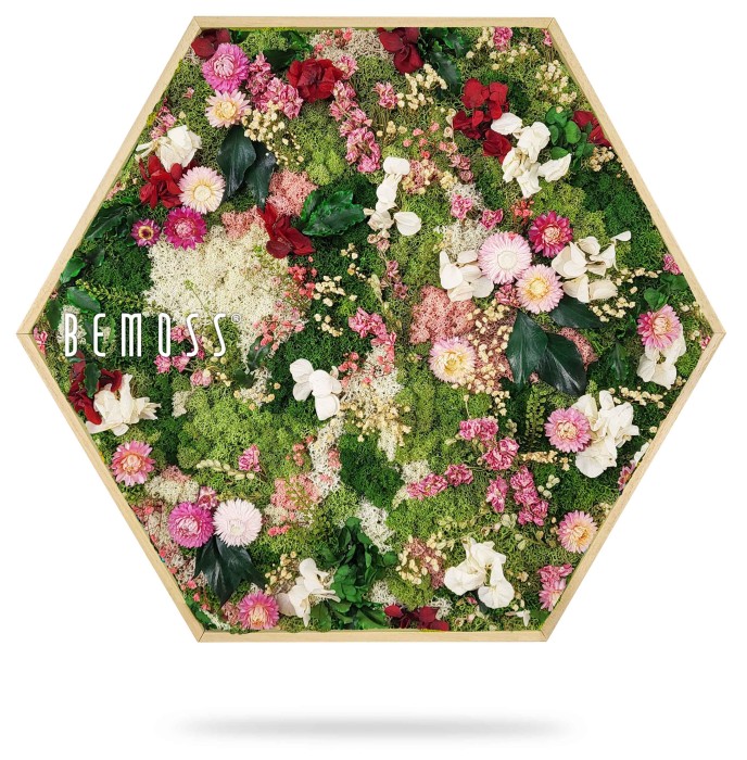 Een zeshoekig houten frame toont een levendig arrangement van gedroogde bloemen, met een mix van roze, witte en rode bloemen afgewisseld met groen blad. Het woord 