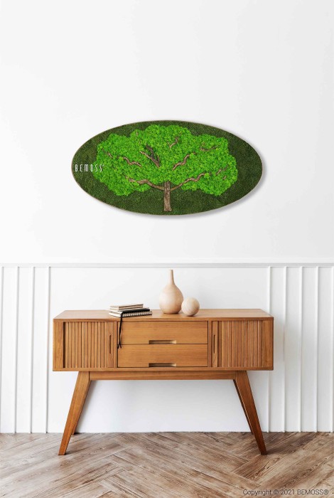 Tegen een witte muur staat een moderne houten consoletafel met twee vazen en een boek erop. Daarboven hangt een ovaalvormige BEMOSS-mosschilderij, met een weelderige groene boom op een groene achtergrond. Het kunstwerk is aan de linkerkant gesigneerd met 
