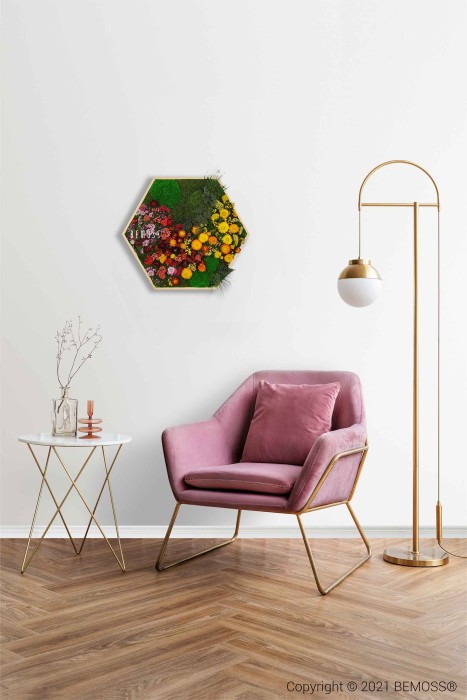 Een stijlvolle woonruimte bestaat uit een roze stoel met kussens en een gouden frame, een hoge vloerlamp met een gouden en witte bollamp en een klein wit bijzettafeltje versierd met decoratieve items. Aan de witte muur is een levendige BEMOSS-mosschilderij met kleurrijke bloemen gemonteerd.
