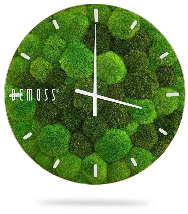 Een wandklok met een wijzerplaat gemaakt van verschillende tinten groen mos, die lijkt op een Mos klok BOLMOSS Minerva met wijzerplaat, gerangschikt in een zeshoekig patroon. De klok heeft eenvoudige witte uren- en minutenwijzers met witte lineaire markeringen voor de uren. Aan de linkerkant wordt de merknaam 