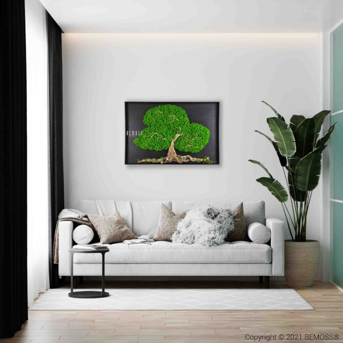 Een moderne woonkamer is voorzien van een witte bank met grijze en beige kussens, een klein zwart bijzettafeltje en een grote potplant. Boven de bank hangt een ingelijst kunstwerk met de afbeelding van Mosschilderij BOOM ARLES. De kamer heeft een lichte houten vloer en vitrages.