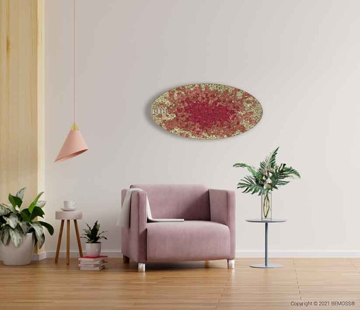 Een minimalistische woonruimte is voorzien van een roze fauteuil naast een moderne bijzettafel met een potplant. De muur is versierd met een ovaalvormig abstract kunstwerk in de kleuren rood en goud, aangevuld met een BEMOSS moschilderij. Aan het plafond hangt een roze hanglamp en planten sieren de vloer en tafel.
