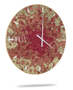 Een ronde wandklok met de merknaam "Mos klok BEMOSS® SPLASH Sienna met dial" siert uw ruimte met zijn unieke textuurontwerp in de kleuren rood, roze en beige. De witte uren- en minutenwijzers glijden over minimalistische markeringen. De klok doet denken aan een BEMOSS-mosschilderij en werpt eronder een intrigerende schaduw.