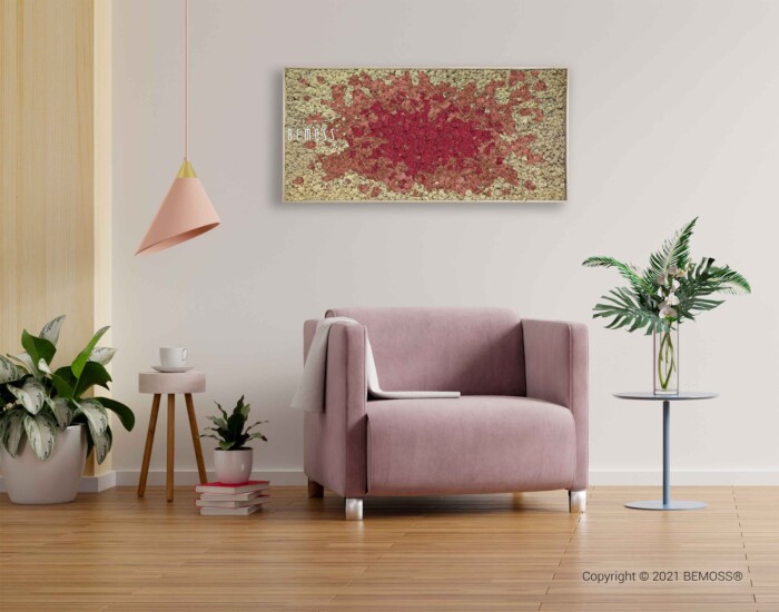Een gezellige woonkamer is voorzien van een zachtroze fauteuil, potplanten en een klein rond bijzettafeltje met een vaas. Aan het plafond hangt een moderne hanglamp, aangevuld met een levendige BEMOSS-mosschilderij aan de muur, die een vleugje artistieke flair aan de ruimte toevoegt.