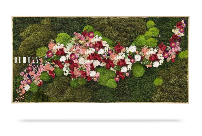 Een rechthoekige wanddecoratie heeft een groene mosachtergrond met verschillende tinten geconserveerd mos en blad. Een diagonale opstelling van rode, roze en witte bloemen accentueert het centrum. Aan de linkerkant staat het woord 